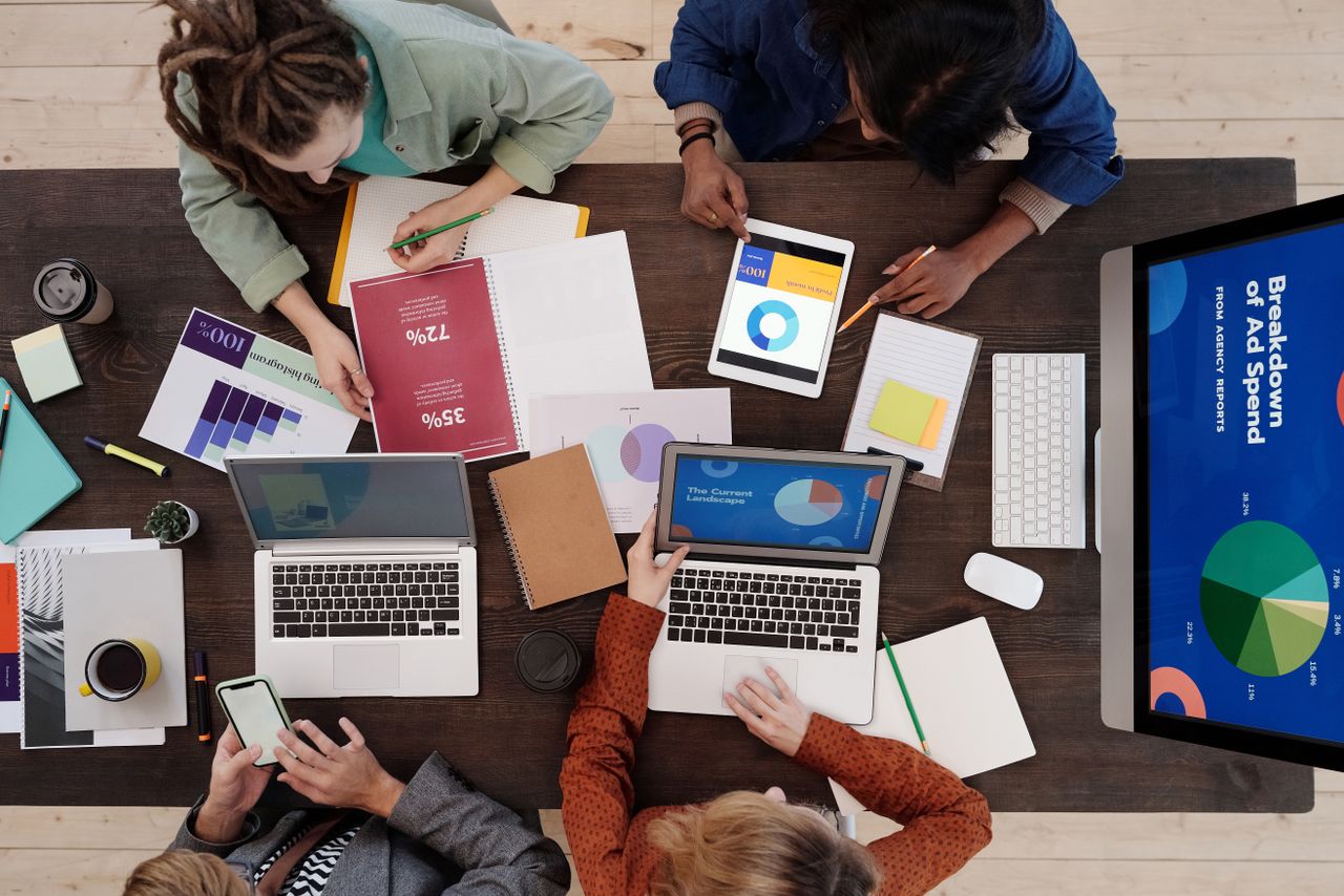 A varied team working together on digital marketing strategies at a desk, using laptops and tablets.